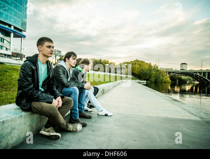 Four friends sitting on conrete wall, Russia Stock Photo