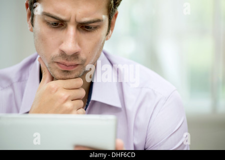 Young man looking at message on digital tablet Stock Photo