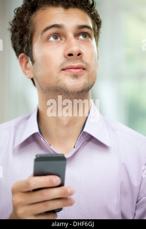 Young man looking up from mobile phone Stock Photo