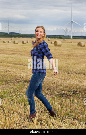 Young woman walking in harvested field Stock Photo