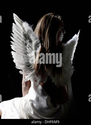 Studio portrait of pensive woman wearing angel wings Stock Photo