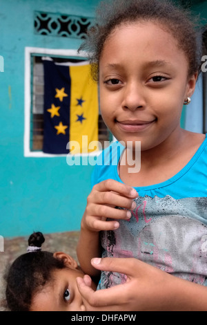 Young Panamanian girls stand next to the flag of Chitre in the town of Chitre in Peninsula de Azuero Herrera province Republic of Panama Stock Photo