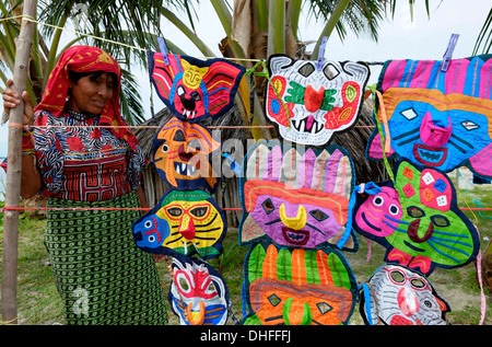 A woman from the Guna people selling selection of elaborate embroidered hand-stitched masks in a small island in the 'Comarca' (region) of the Guna Yala natives known as Kuna located in the archipelago of San Blas Blas islands in the Northeast of Panama facing the Caribbean Sea. Stock Photo