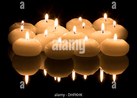 White candles on a black reflecting background Stock Photo