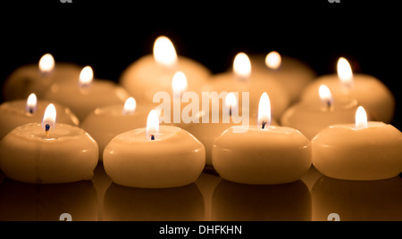 White candles on a black reflecting background Stock Photo