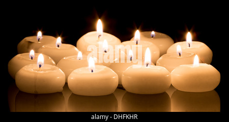 White candles on a black reflecting background Stock Photo
