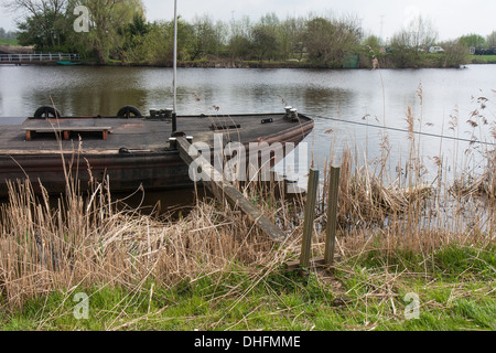 Old iron freighter moored in a river along cane vegetation Stock Photo
