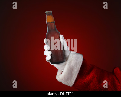 Closeup of Santa Claus holding a bottle of beer. Only hand and arm are visible. Stock Photo