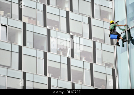 Window washer working high up on modern office building Stock Photo