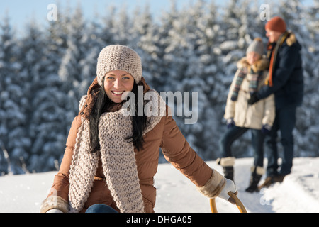 Winter young people friends enjoy snow on wooden sledge sunny Stock Photo