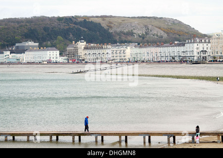 Person wearing a red cap walking along a jetty at Llandudno, Conwy County Borough, North Wales Stock Photo