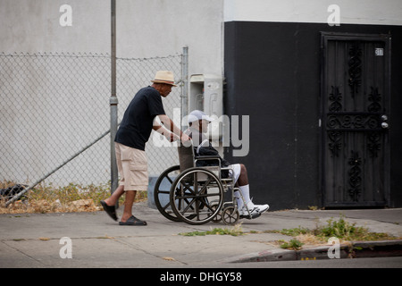 Man pushing elderly man on wheelchair Stock Photo