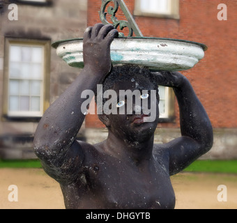 Black African holding sundial at Dunham Massey Hall , near Altrincham Cheshire England , UK WA14 4SJ. BLM, Black Statue, Do Black Lives Matter? Stock Photo