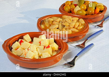 Selection of tapas - From front to back: Cubed Manchego cheese in olive oil with chilli, White beans and pork. Stock Photo