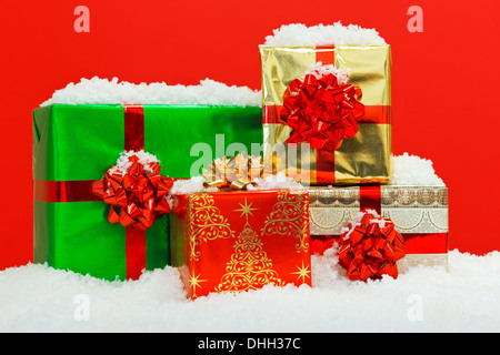 Christmas gift wrapped presents on snow with red background. Stock Photo