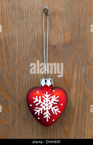 Red heart shaped Christmas ornament hanging by a rusty nail on an old wooden door Stock Photo