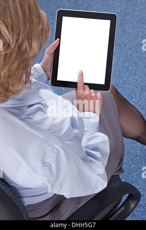 Businesswoman sat in an office using a tablet computer. Clipping path provided for the screen to add your own message or image. Stock Photo