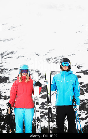 Young people wearing skiwear carrying skis Stock Photo