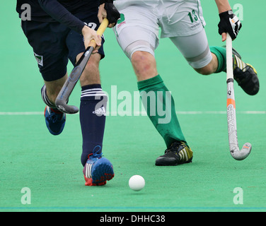 Waist down shot of two field hockey players with hockey sticks running towards the camera while competing for the ball. Stock Photo