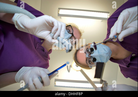 Dentist and dental nurse leaning forward holding dental equipment Stock Photo