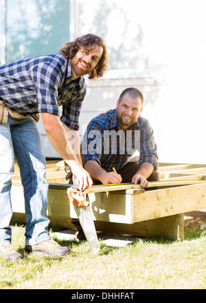 Workers Measuring Wood Together At Construction Site Stock Photo