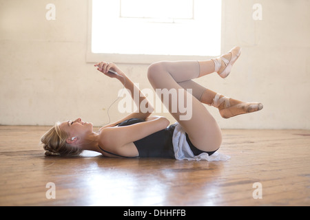 Ballet dancer lying on floor listening to music Stock Photo
