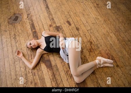 Ballet dancer lying on wooden floor Stock Photo