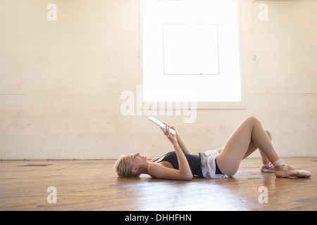 Ballet dancer lying on floor holding digital tablet Stock Photo