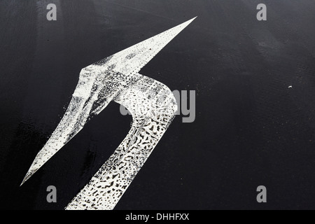 white painted road arrow marking on a black road surface Stock Photo
