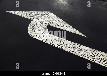 white painted road arrow marking black road Stock Photo