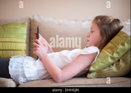 girl on a sofa using an ipad tablet computer Stock Photo