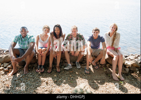 Portrait of friends sitting on stone wall Stock Photo