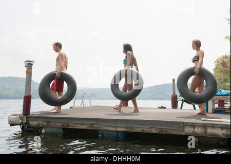 Friends on jetty carrying inflatable rings Stock Photo