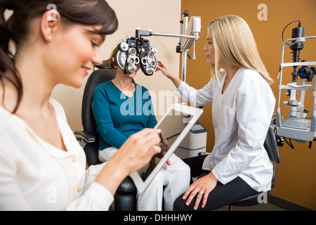 Optometrists Examining Senior Woman In Store Stock Photo