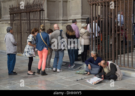 Homeless couple begging outside Granada Cathedral, or the Cathedral of the Incarnation (Spanish: Catedral de Granada, Catedral de la Anunciación) is the cathedral in the city of Granada, capital of the province of the same name in the Autonomous Region of Andalusia, Spain. The cathedral is the seat of the Archdiocese of Granada. Stock Photo