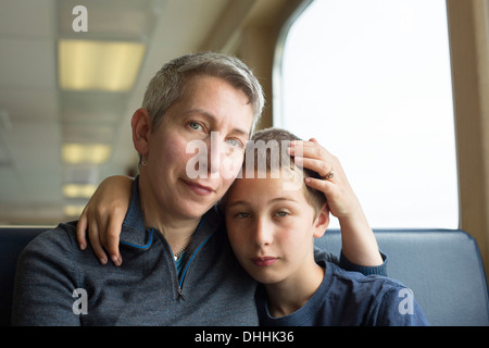 Mother and son sitting together with arm around Stock Photo