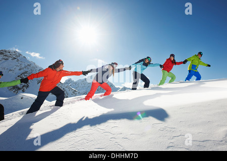 Friends pulling each other uphill in snow, Kuhtai, Austria Stock Photo