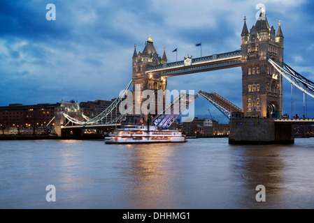 Open Tower Bridge against stormy sky with boat passing under cantilevers Stock Photo
