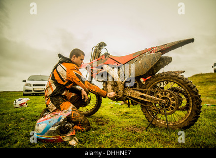 Teenage boy checking motorcycle at motocross Stock Photo