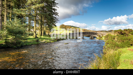 The East Dart River flowing through an old granite bridge at Bellever Forest on Dartmoor Stock Photo