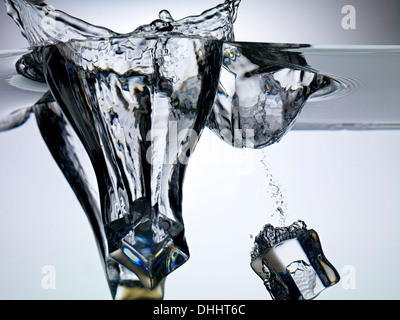 Ice cubes dropping into water Stock Photo