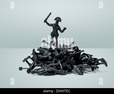 Heroic toy soldier standing on top of a pile of defeated toy soldiers. Stock Photo