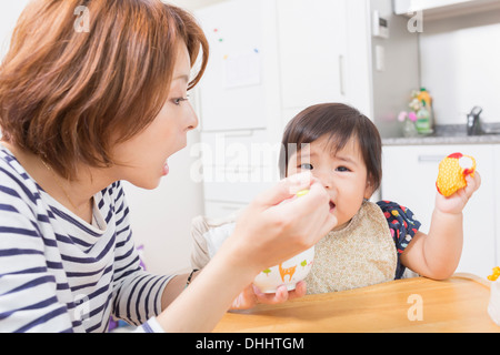 Mother feeding baby in kitchen Stock Photo