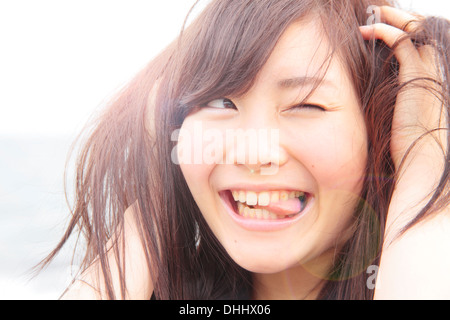 Portrait of young woman, hands in hair, sticking tongue out Stock Photo