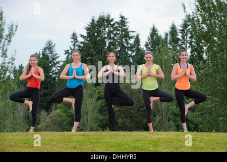 Teenage girls and yoga tutor doing tree poses Stock Photo