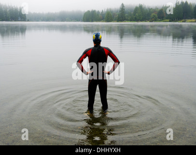 Young man in wet suit preparing to swim lake Stock Photo