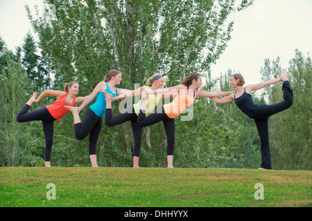 Teenage girls and yoga tutor standing on one leg Stock Photo