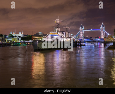HMS Belfast, Tower Bridge and Tower of London on River Thames, London, UK at night Stock Photo