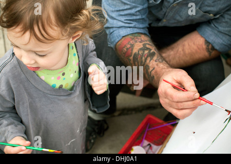 Father and daughters painting on easel Stock Photo