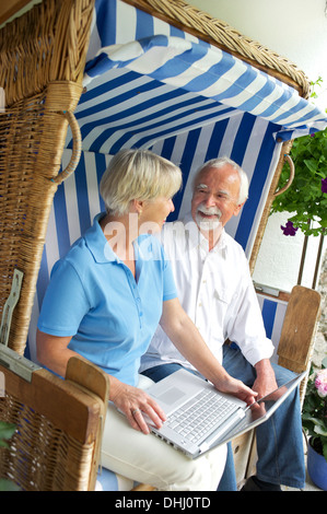 Retired couple using laptop on garden seat Stock Photo